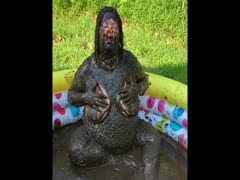 Pervert pig bathing in a black wet shit outdoors
